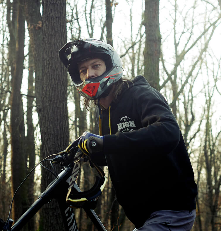Rider in a Too High To Die hoodie on a bike in a wintry forest