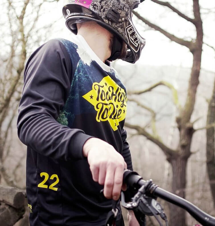 Close-up of a long-sleeve Too High To Die jersey on a rider in a full-face helmet