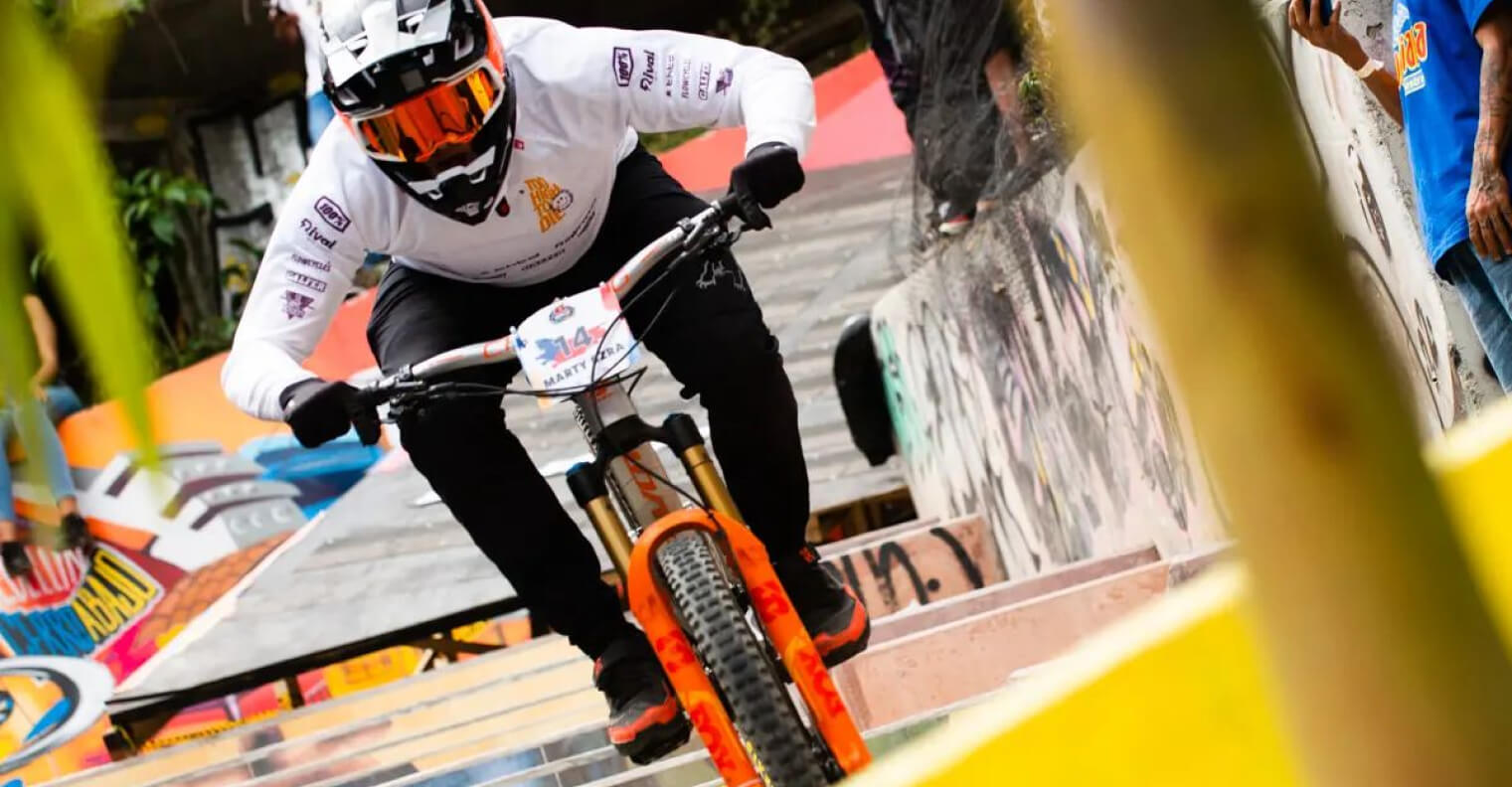 Urban downhill – a racer in a Too High To Die jersey on city stairs