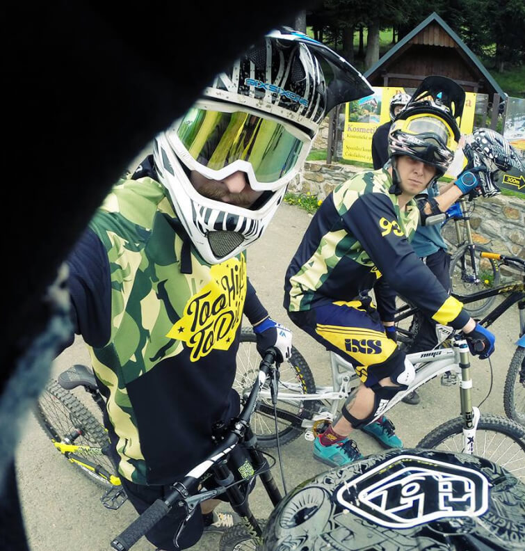 Two riders in camo Too High To Die jerseys and full-face helmets at a bike park